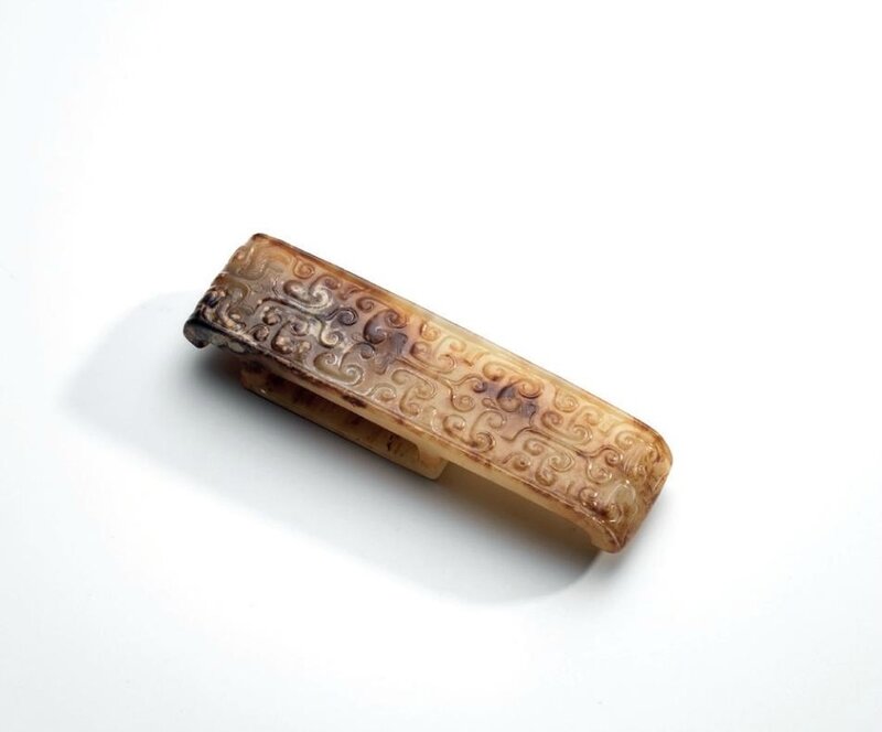 A white and russet jade 'Comma scroll' scabbard slide, Warring States period (475-221 BC)