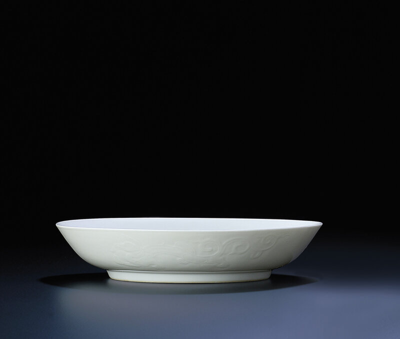A fine and rare pair of white-glazed moulded 'dragon' dishes, Yongzheng six-character marks within double-circles and of the period (1723-1735)