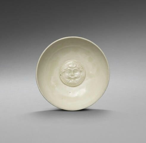 A rare northern Xingyao relief-moulded 'smiling mask' bowl Northern DynastiesSui Dynasty