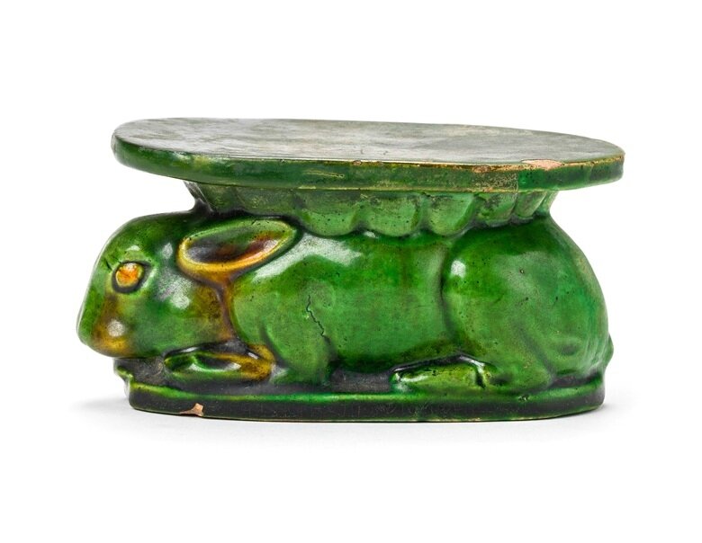 A green and amber-glazed rabbit-form pillow
